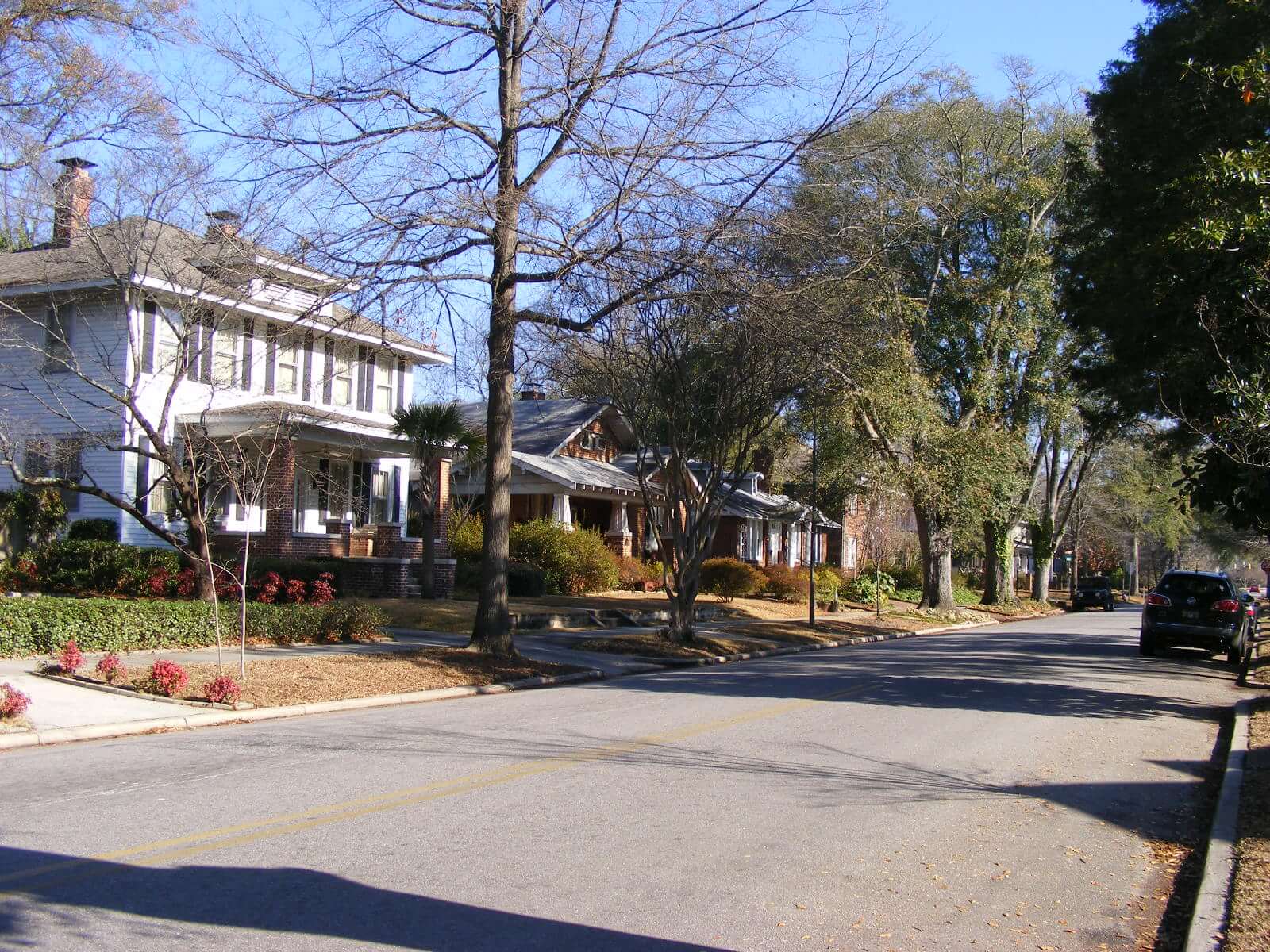 Photograph of a street with one and two story wood-sided and brick homes