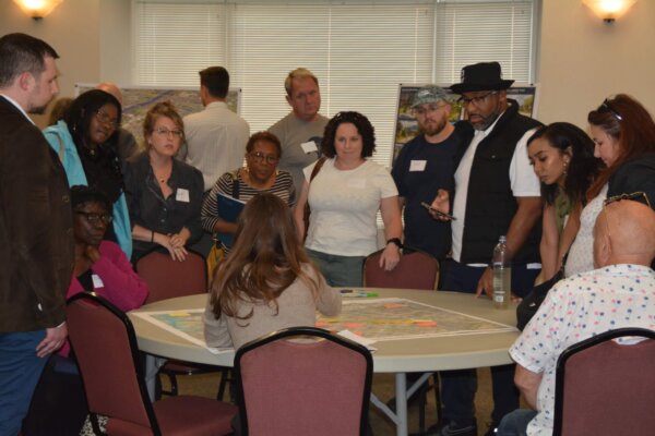 A photo of individuals gathered around a table with maps at the design workshop.