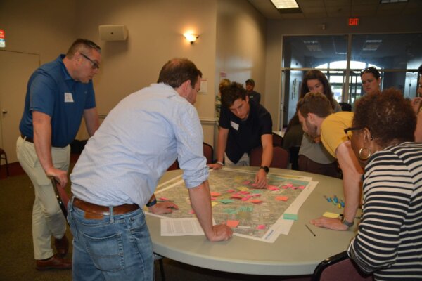 A photo of individuals gathered around a table with maps at the design workshop.