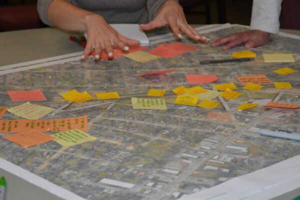 A photo of hands above a map covered with sticky notes with comments in various colors