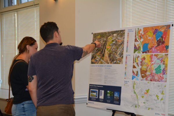a photo of individuals standing and pointing at display boards that gave context to the process