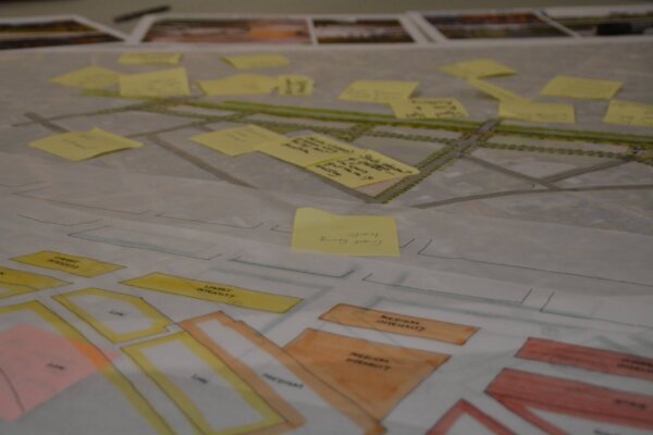 a photo of tracing paper with some early concepts, and a conceptual design with sticky notes in the background