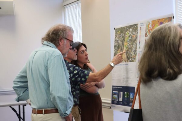 a photo of individuals standing and pointing at display boards that gave context to the process